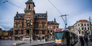 Scène urbaine à Anderlecht avec un camion de plombier garé devant une maison typiquement bruxelloise.