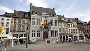 Plombier Ath travaillant près de l'Hôtel de Ville d'Ath, Belgique, avec ses façades historiques et rues pavées pittoresques.