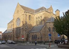 Débouchage Berchem Sainte Agathe canalisation dans rue pavée avec maisons en briques typiques et arbres verdoyants