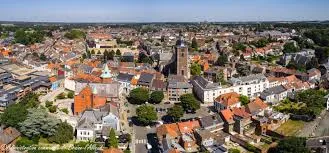 Centre-ville de Braine-l'Alleud avec enseigne de plombier local, architecture typique et passants animés.