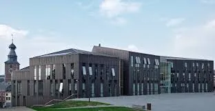 Plombier Gembloux devant l'Hôtel de Ville historique, quartier animé avec maisons en briques rouges et commerces locaux.