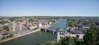 Scène urbaine avec vue sur la Collégiale Notre-Dame de Huy et camion de plombier garé devant, travail local Plombier Huy.